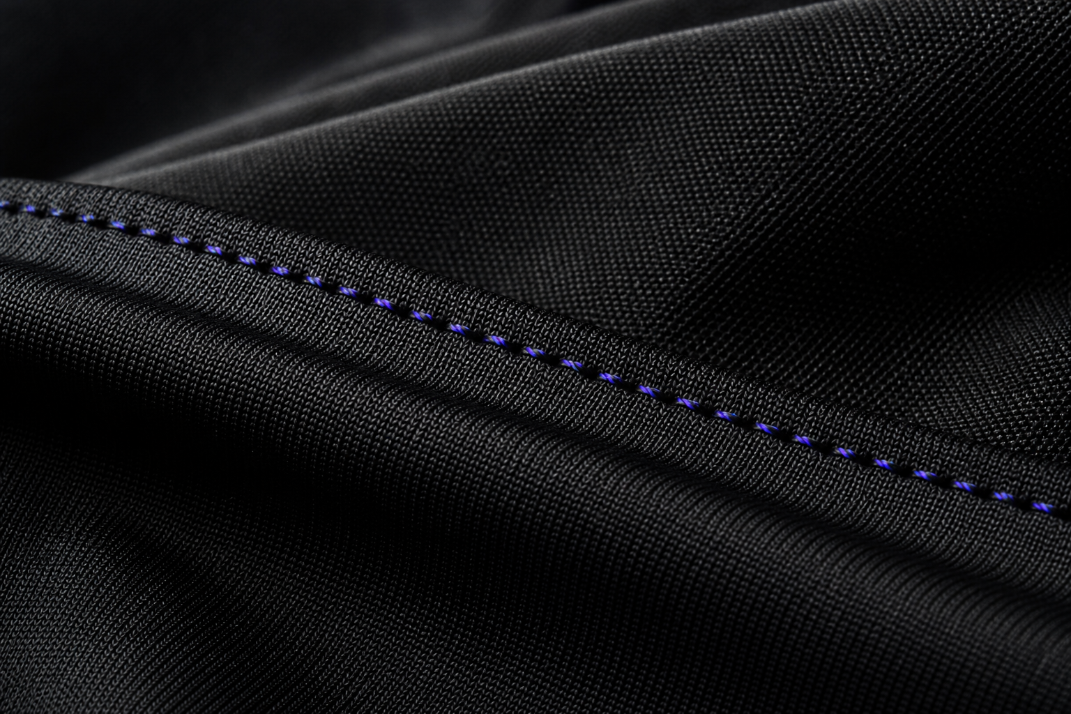 Macro detail of black technical fabric with an aurora stitch
